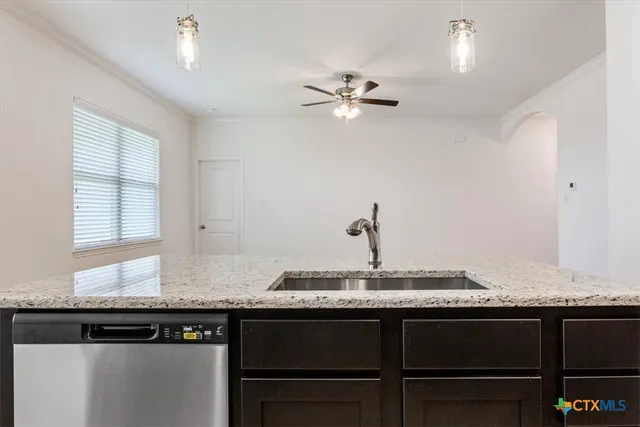 a kitchen with granite countertop a sink cabinets and stainless steel appliances