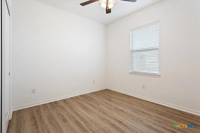 an empty room with a window and a ceiling fan