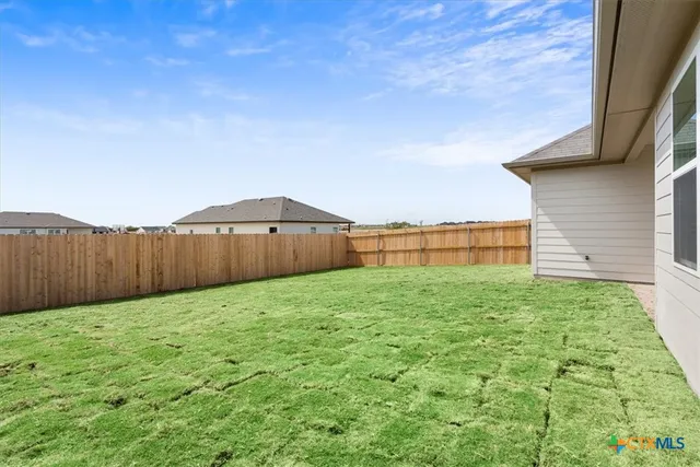 a view of backyard with wooden fence