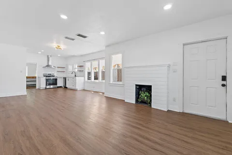a view of a livingroom with a fireplace a window and wooden floor