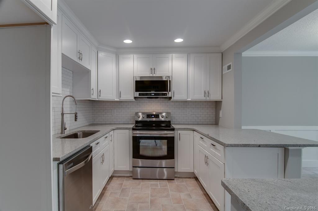83 Ridgeport Road, Unit 83B Lake Wylie, SC 29710 - Photo 3 of 24 a kitchen with stainless steel appliances granite countertop a stove top oven a sink and white cabinets
