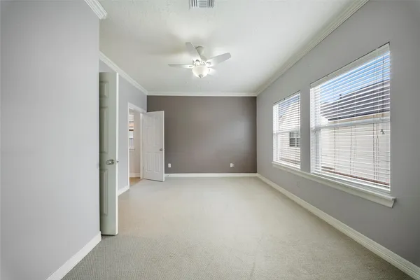 an empty room with chandelier fan and windows