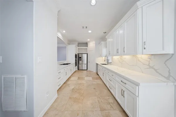 a large white kitchen with center island and stainless steel appliances