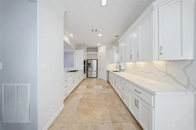 a large white kitchen with center island and stainless steel appliances