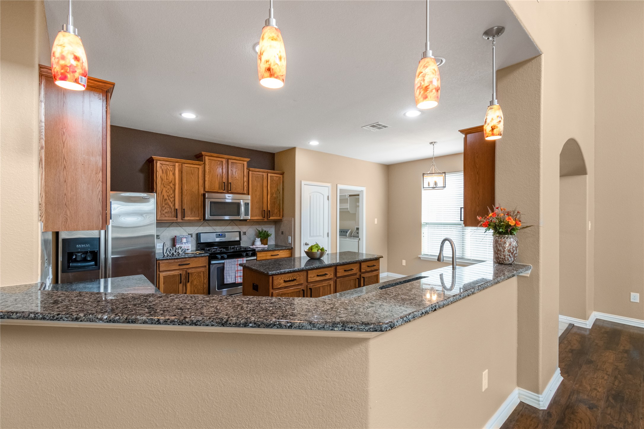3413 Grail Hollows Road Pflugerville, TX 78660 - Photo 12 of 36 Kitchen with wood finish cabinets, a kitchen island, decorative light fixtures, and a peninsula