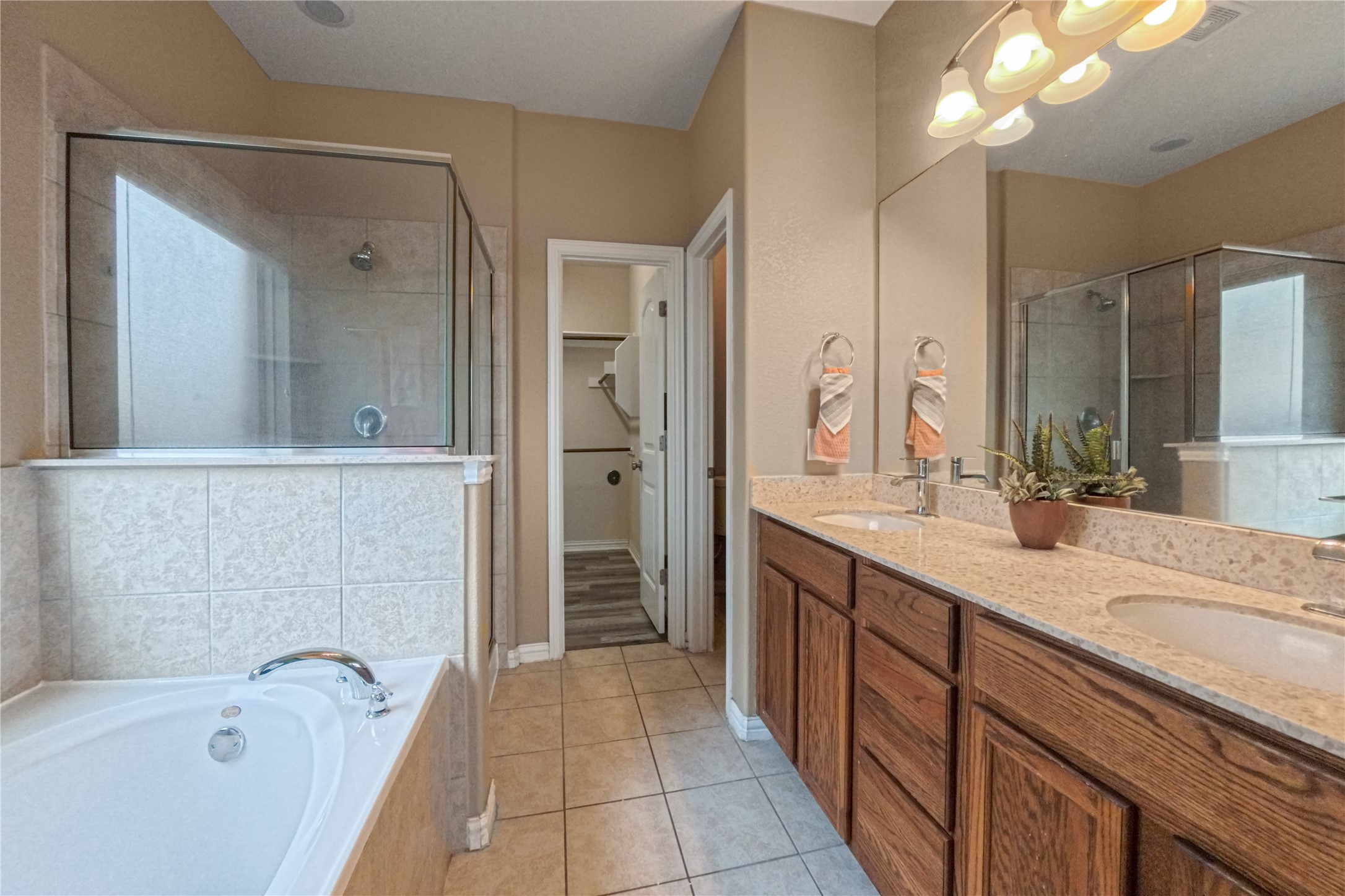 3413 Grail Hollows Road Pflugerville, TX 78660 - Photo 20 of 36 Bathroom with light tile patterned floors, a walk in closet, double vanity, a stall shower, and a garden tub