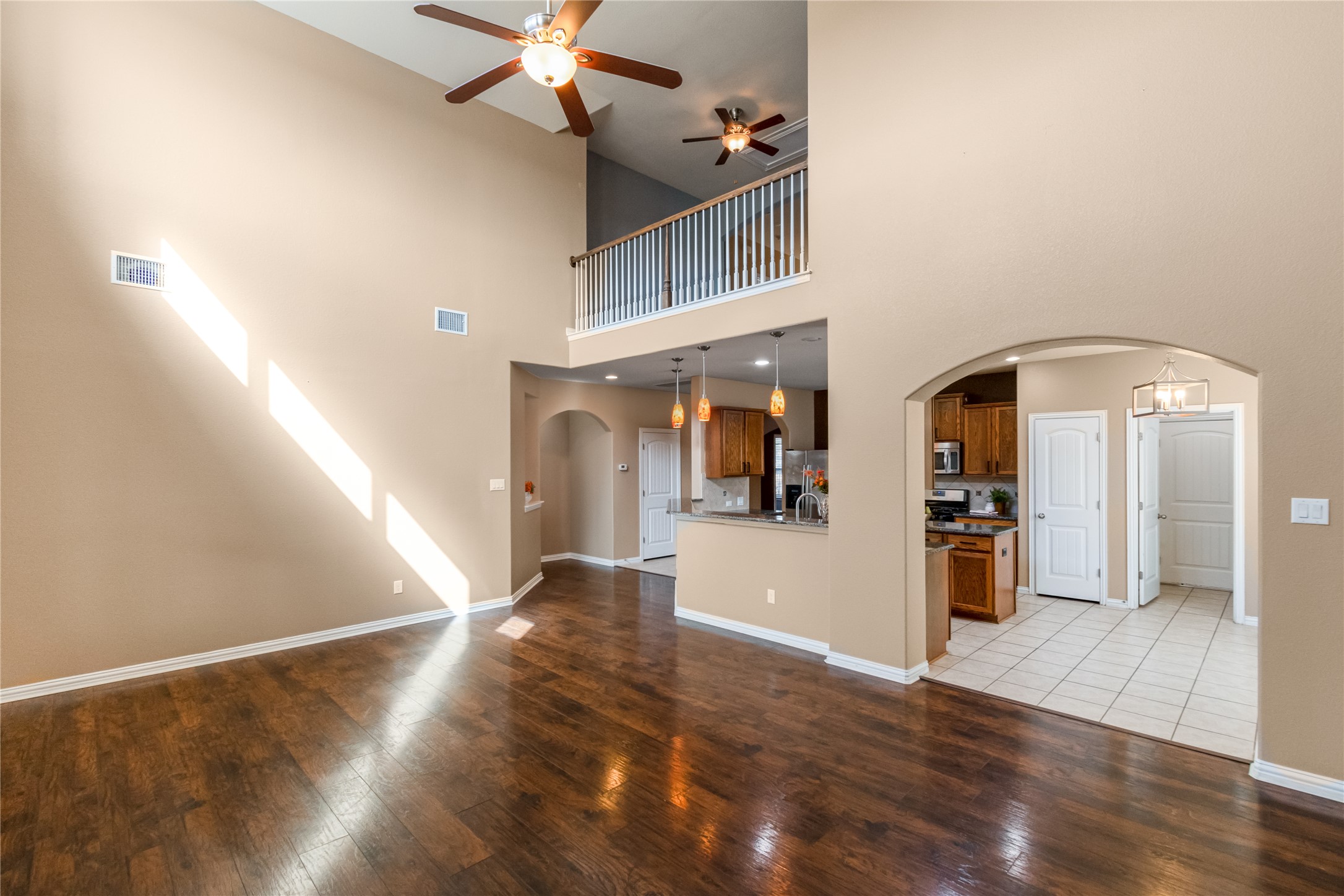3413 Grail Hollows Road Pflugerville, TX 78660 - Photo 6 of 36 Unfurnished living room featuring arched walkways, ceiling fan, hardwood / wood-style flooring, and a high ceiling