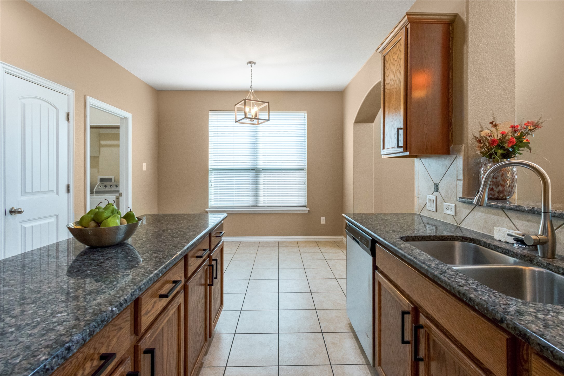 3413 Grail Hollows Road Pflugerville, TX 78660 - Photo 8 of 36 Kitchen featuring wood finish cabinetry, dark stone countertops, light tile patterned floors, and dishwasher
