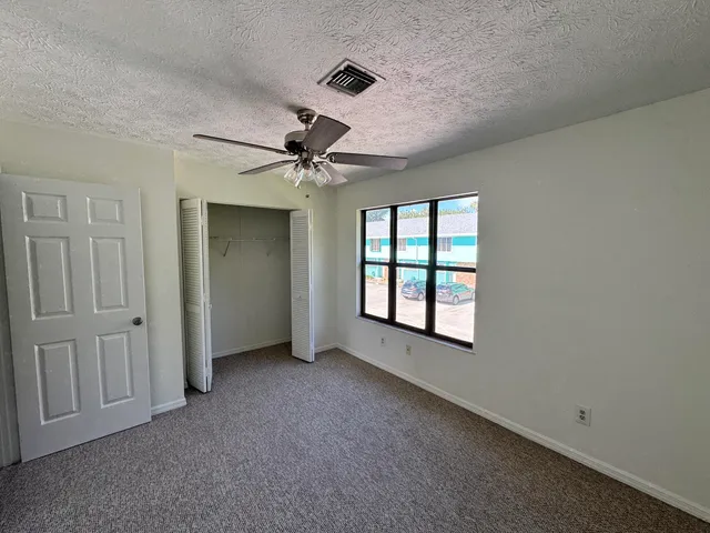 an empty room with windows and fan