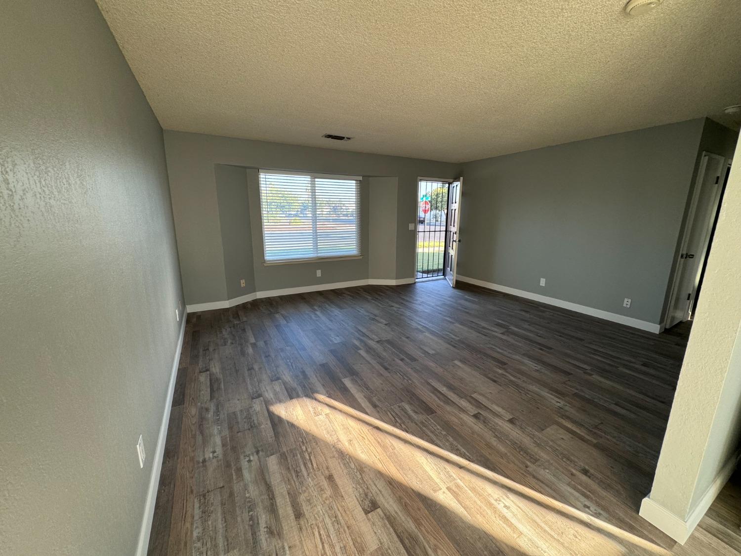 1306 13th Street Reedley, CA 93654 - Photo 4 of 14 wooden floor in an empty room with a window