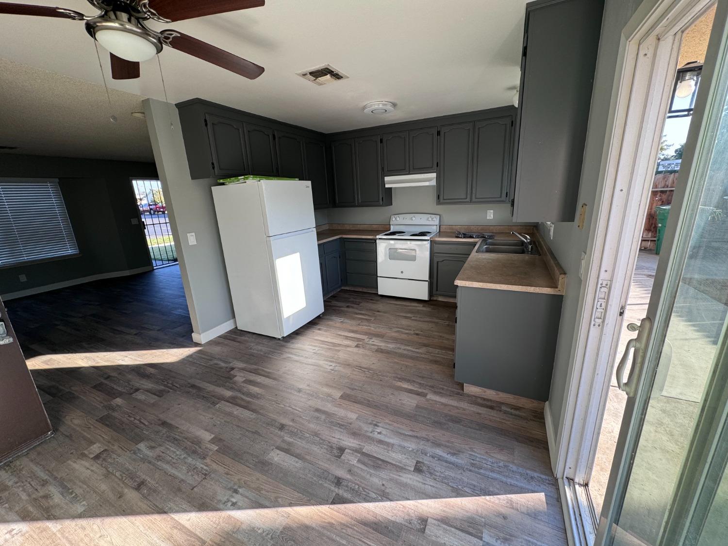 1306 13th Street Reedley, CA 93654 - Photo 8 of 14 a view of a kitchen with fridge and wooden floor