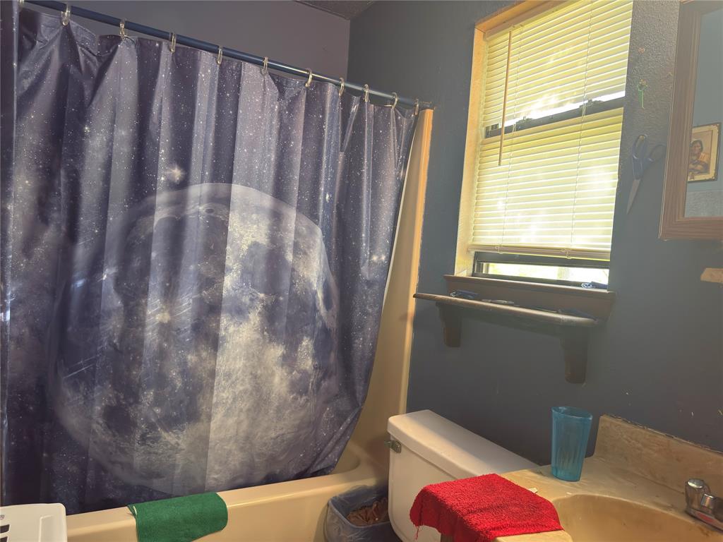 12776 Valverde Loop Terrell, TX 75161 - Photo 33 of 36 a bathroom with a toilet and shower curtain