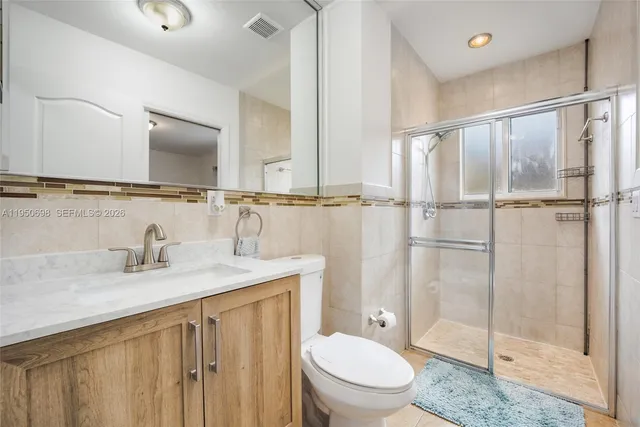 a bathroom with a granite countertop sink toilet and shower