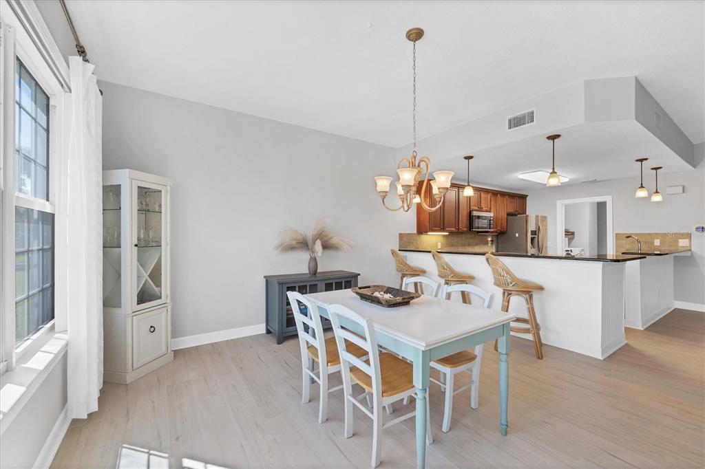 10720 Lemon Creek Loop, Unit 103 Englewood, FL 34224 - Photo 11 of 57 a dining room with furniture a chandelier and wooden floor