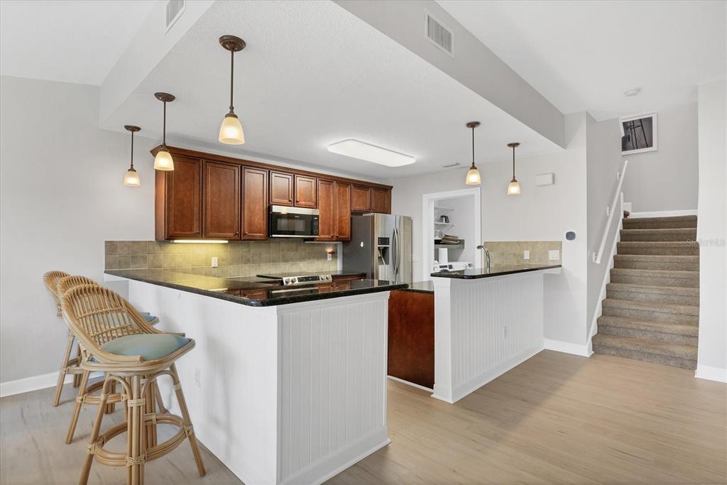 10720 Lemon Creek Loop, Unit 103 Englewood, FL 34224 - Photo 14 of 57 a kitchen with stainless steel appliances granite countertop a stove a sink a refrigerator and island with wooden floor