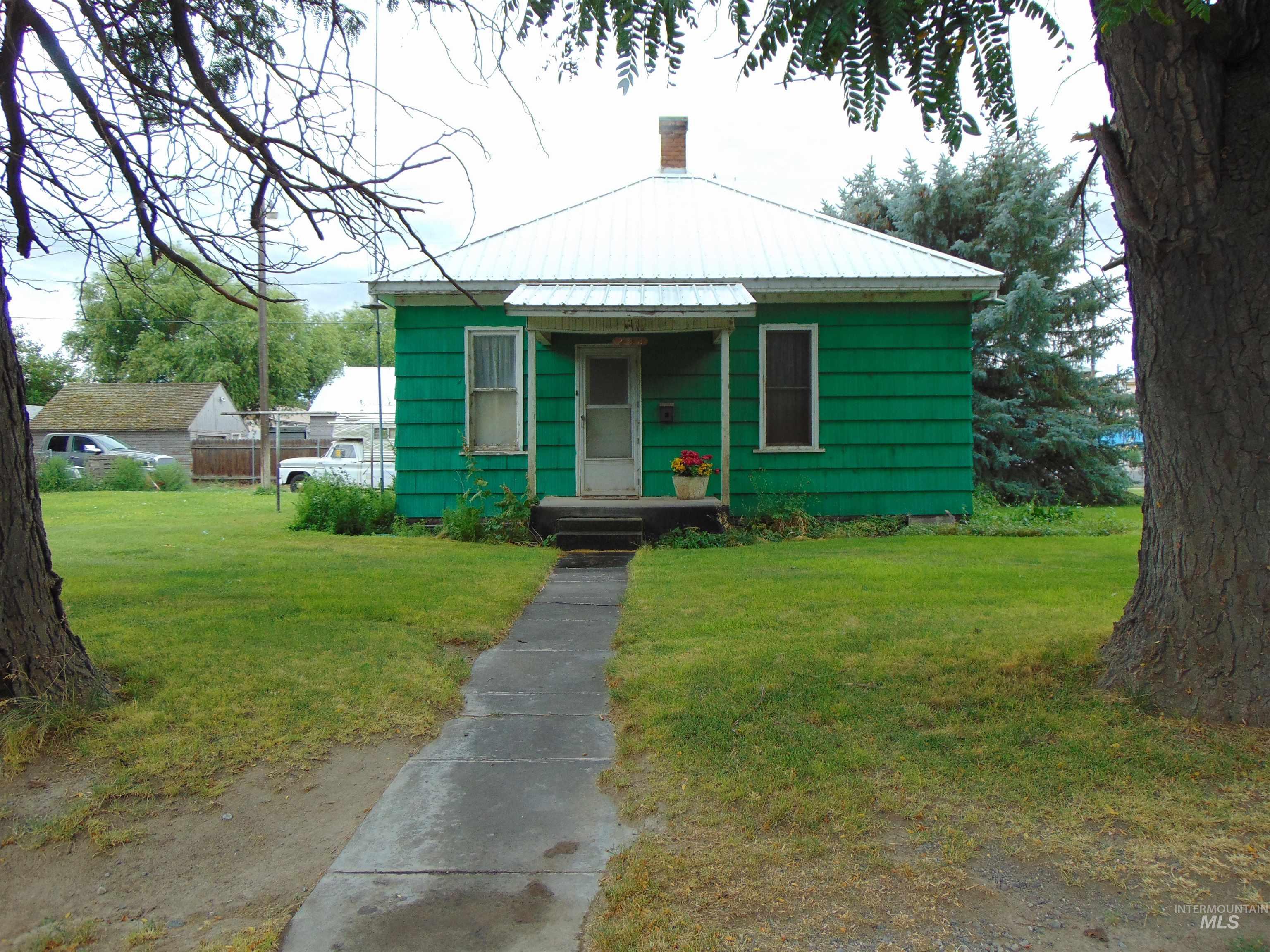 Bungalow-style home featuring a front lawn, a metal roof, and a chimney