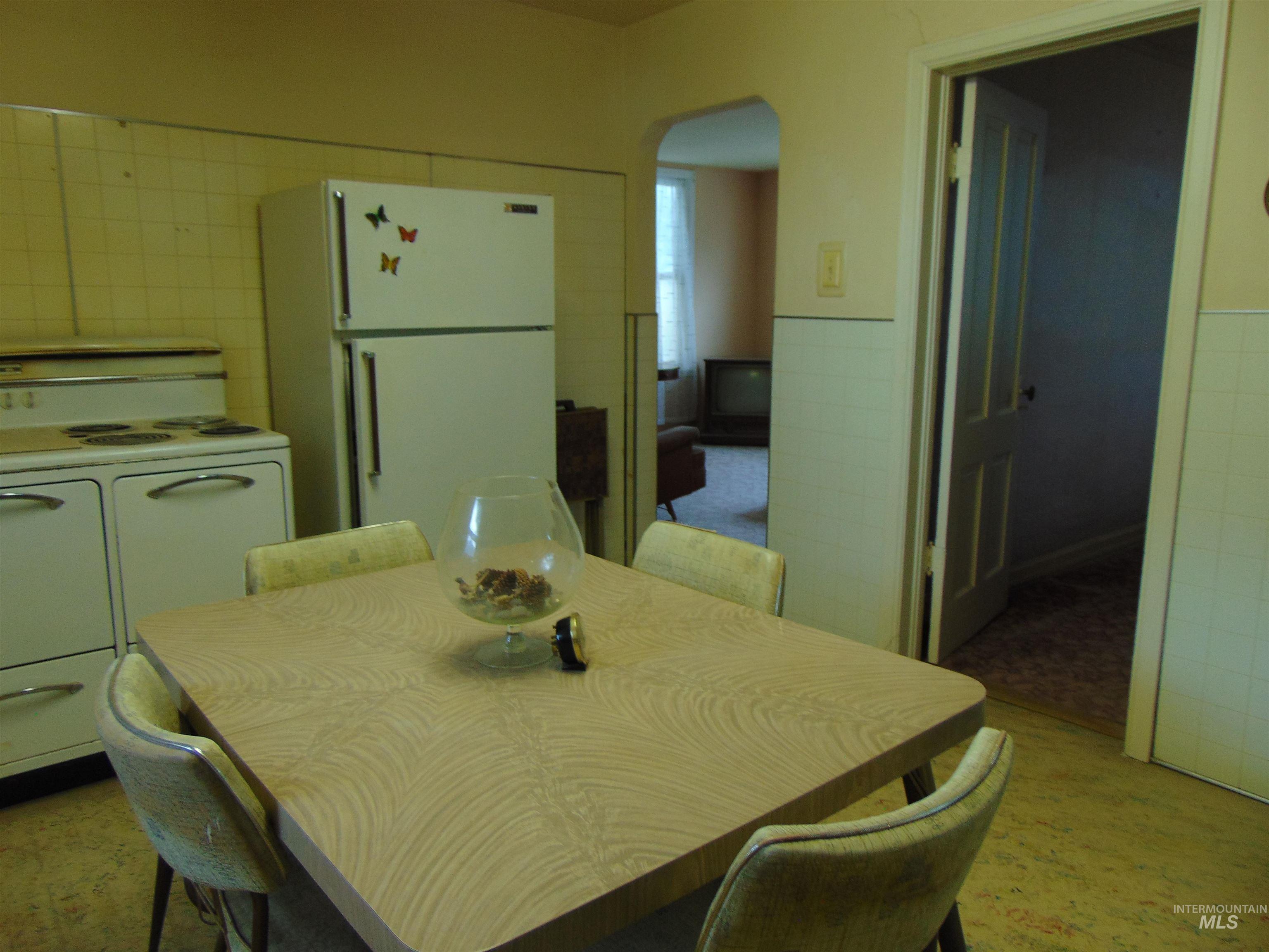 233 Glenn Street South Vale, OR 97918 - Photo 7 of 13 Dining area featuring tile walls, arched walkways, a wainscoted wall, and light carpet