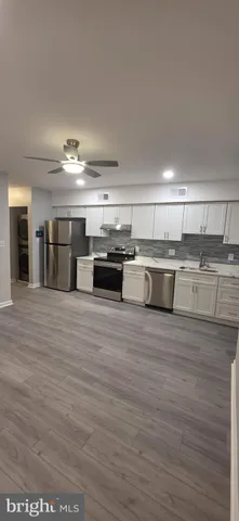 a large white kitchen with stainless steel appliances wooden floor