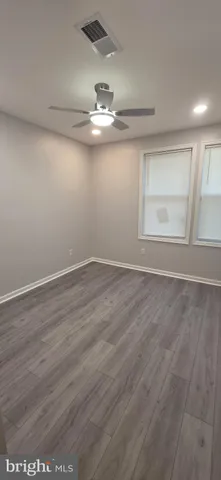 an empty room with wooden floor and ceiling fan