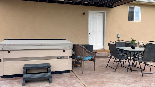 1797 Sunset Road Enoch, UT 84721 - Photo 55 of 80 Private patio featuring a built-in hot tub, concrete paving, direct access via a white paneled door, and a soffit overhead