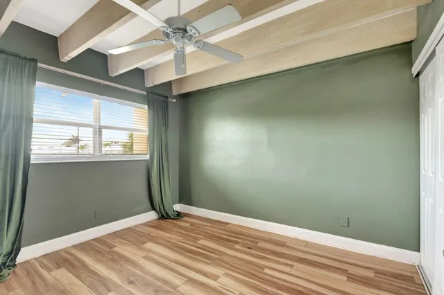an empty room with wooden floor and fan