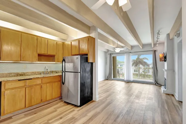 a kitchen with a refrigerator wooden floor and window