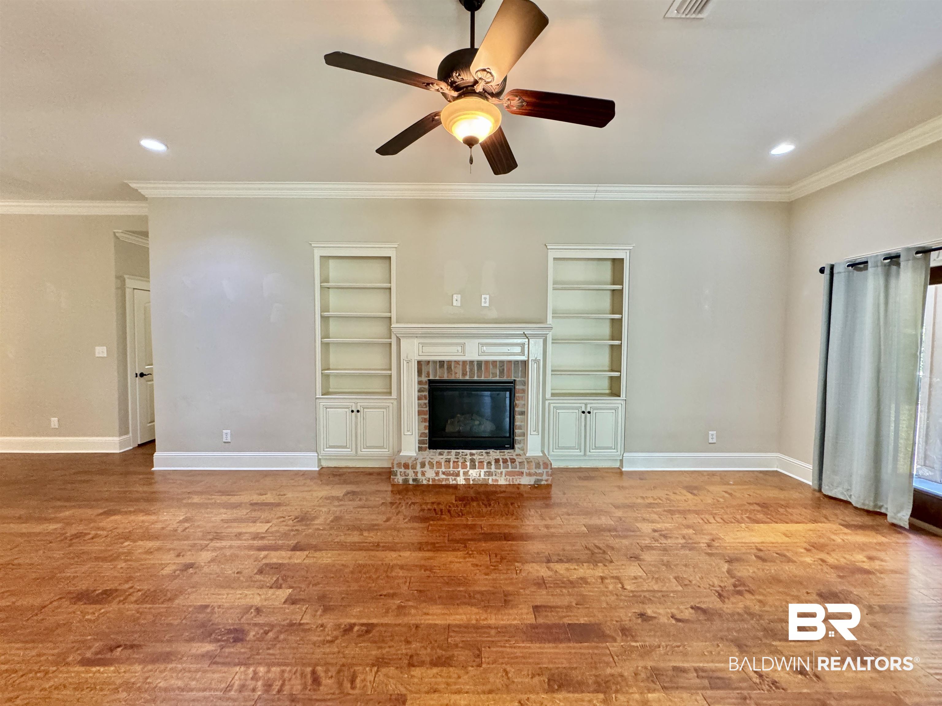 10846 County Road 138 Bay Minette, AL 36507 - Photo 11 of 53 Unfurnished living room featuring ornamental molding, a brick fireplace, built in features, light hardwood / wood-style floors, and ceiling fan