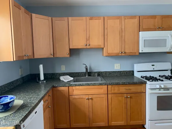 a kitchen with granite countertop a sink a stove and cabinets