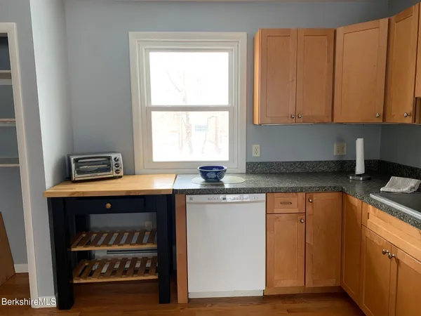 a kitchen with granite countertop a stove a sink and dishwasher with wooden floor