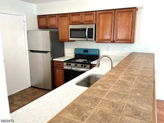 a kitchen with granite countertop a refrigerator stove and microwave