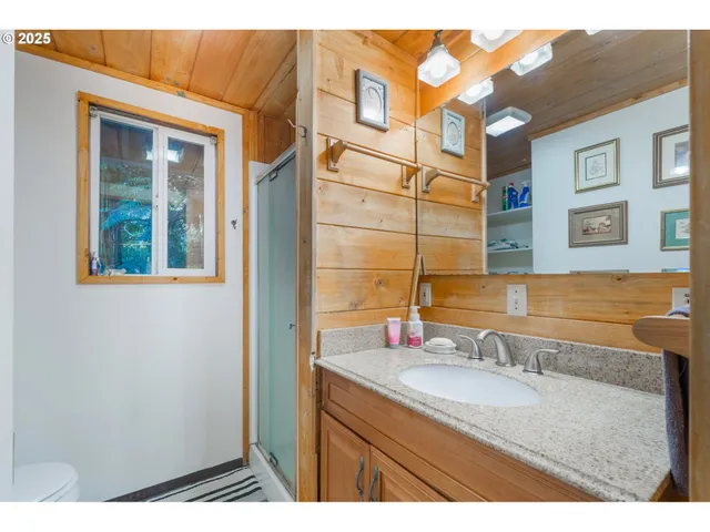 a bathroom with a granite countertop sink a mirror and a shower
