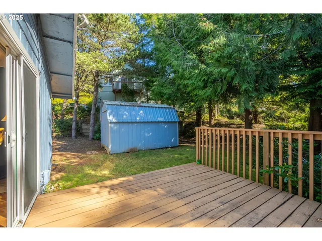a view of backyard with a deck and wooden fence