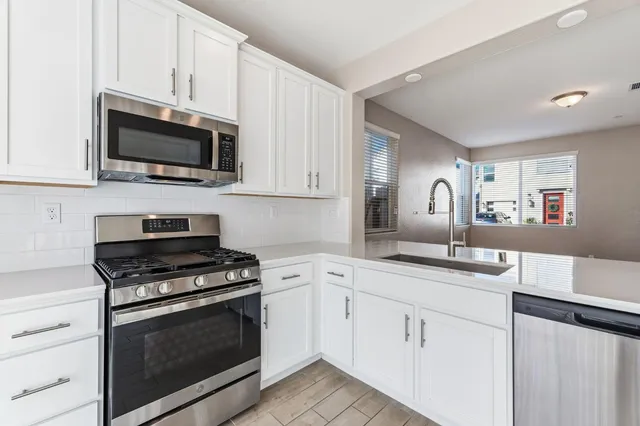 a kitchen with white cabinets and appliances