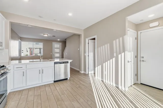 a large white kitchen with a sink and dishwasher a stove with wooden floor