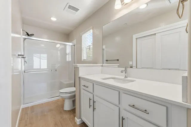 a bathroom with a sink a toilet a mirror and shower