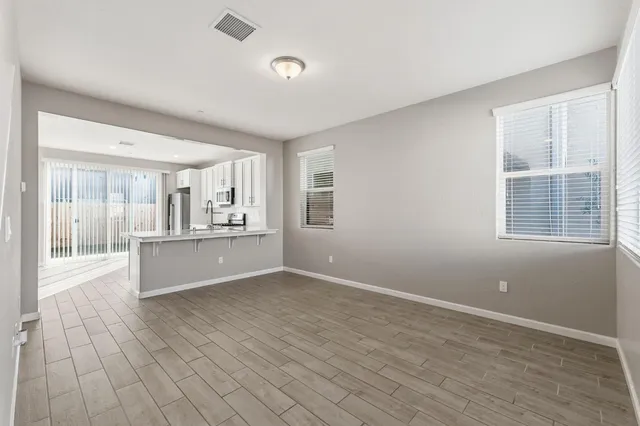 a view of kitchen and empty room with wooden floor and windows