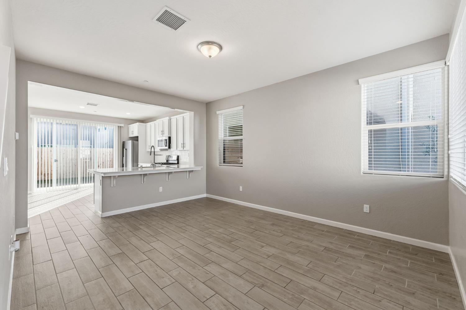 1116 Elevations Way West Madera, CA 93636 - Photo 7 of 35 a view of kitchen and empty room with wooden floor and windows