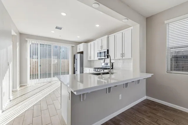 a kitchen with kitchen island a sink appliances cabinets and a large window