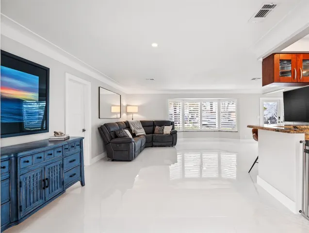 a living room with furniture a flat screen tv and a refrigerator