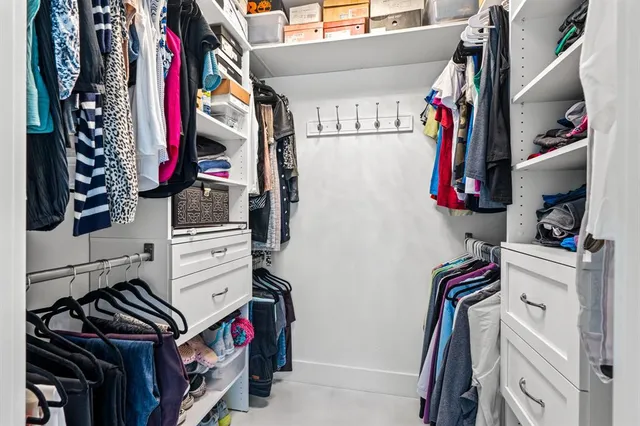 a view of walk in closet with clothes and shoes