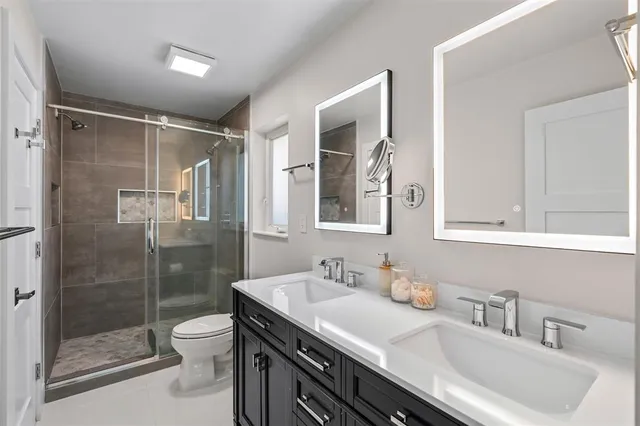 a bathroom with a granite countertop sink a toilet a mirror and shower