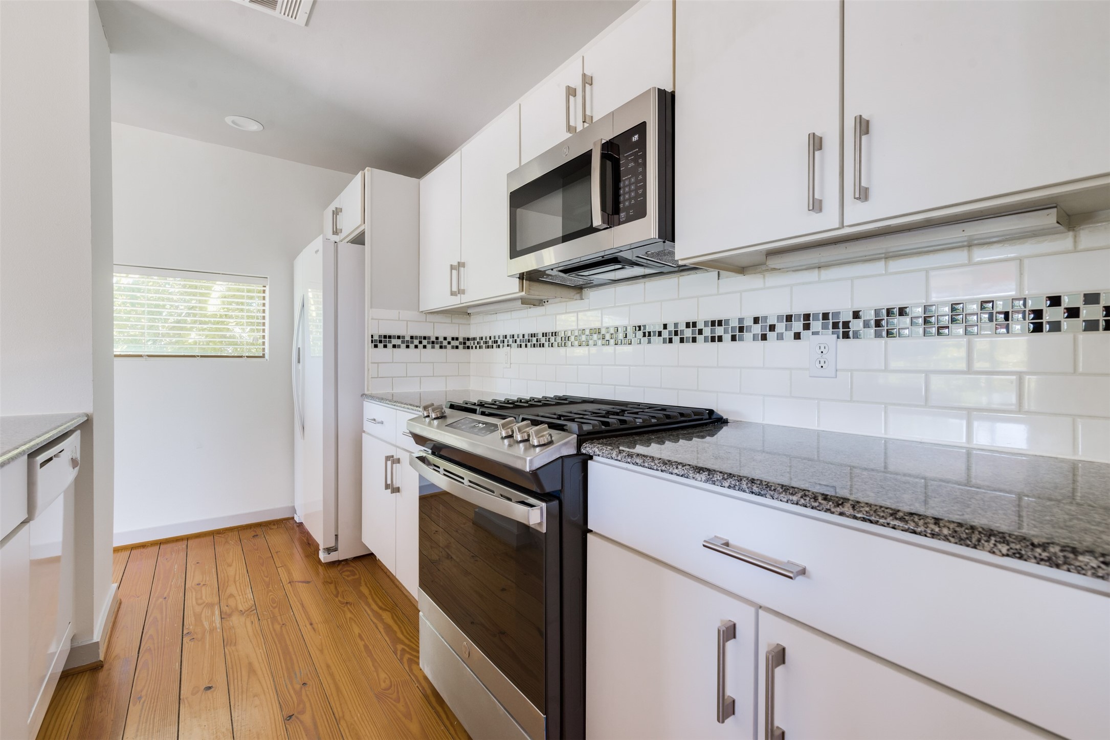 2605 Calumet Street, Unit 48 Houston, TX 77004 - Photo 20 of 34 a kitchen with granite countertop wooden cabinets stainless steel appliances and a wooden floor