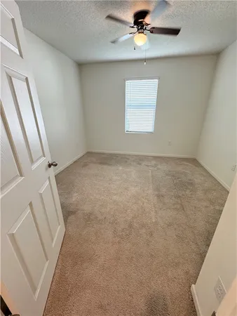 an empty room with windows and ceiling fan