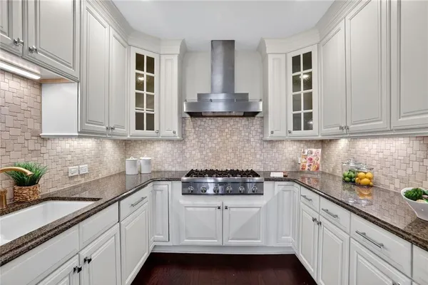 a kitchen with stainless steel appliances granite countertop white cabinets and a stove