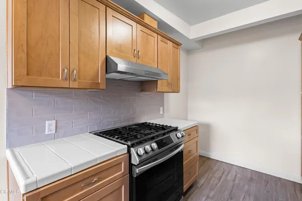 a kitchen with granite countertop a stove and a wooden cabinets