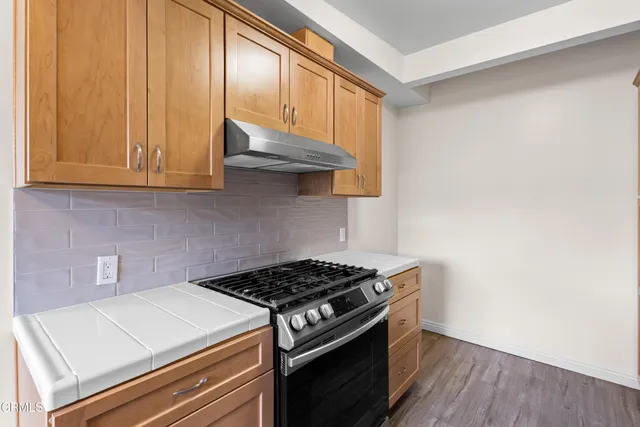 a kitchen with granite countertop a stove and a wooden cabinets