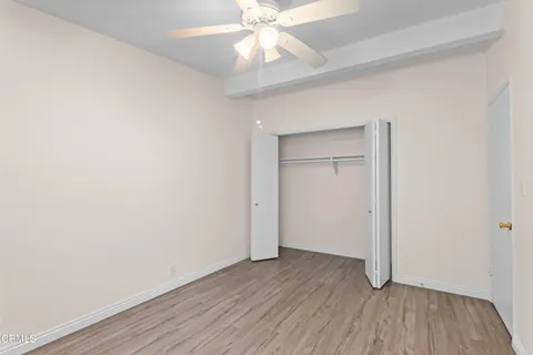 an empty room with wooden floor closet and windows