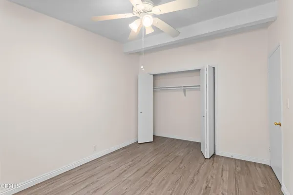 an empty room with wooden floor closet and windows