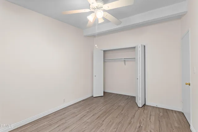 an empty room with wooden floor closet and windows