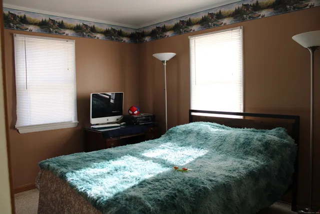 a bedroom with a bed and a flat tv screen on dresser